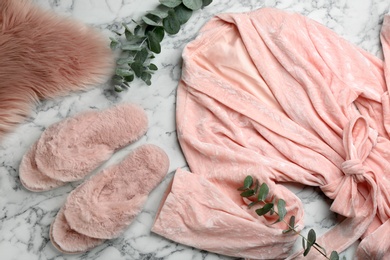 Photo of Flat lay composition with fluffy slippers and robe on white marble background. Comfortable home outfit