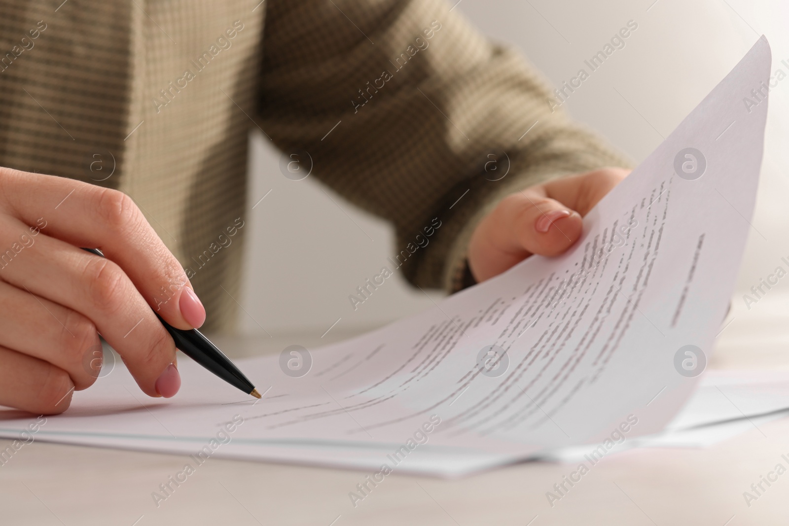 Photo of Woman signing document at table, closeup view