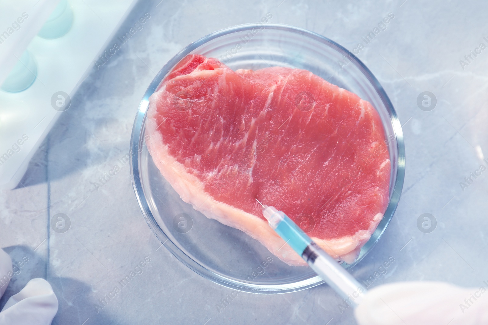 Photo of Scientist injecting liquid into meat sample on table, closeup. Food quality control