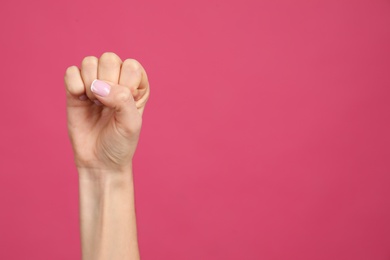Photo of Closeup view of woman showing fist as girl power symbol on pink background, space for text. 8 March concept
