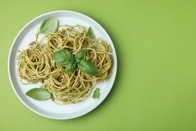 Photo of Delicious pasta with pesto sauce and basil on light green background, top view. Space for text