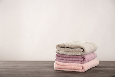 Photo of Stack of color towels on wooden table. Space for text