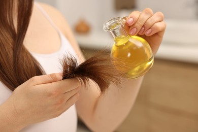 Photo of Woman applying oil hair mask at home, closeup
