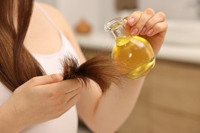 Woman applying oil hair mask at home, closeup