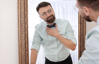 Young handsome man near mirror in makeup room