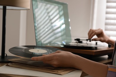 Young woman using turntable at home, closeup