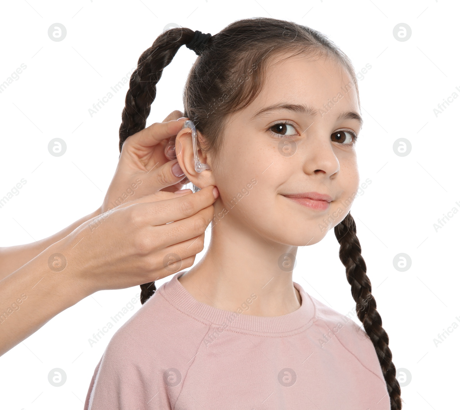 Photo of Young woman putting hearing aid in little girl's ear on white background