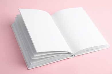 Photo of Open book with blank pages on pink background