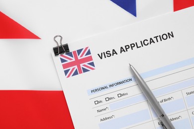 Immigration to United Kingdom. Visa application form and pen on flag, top view