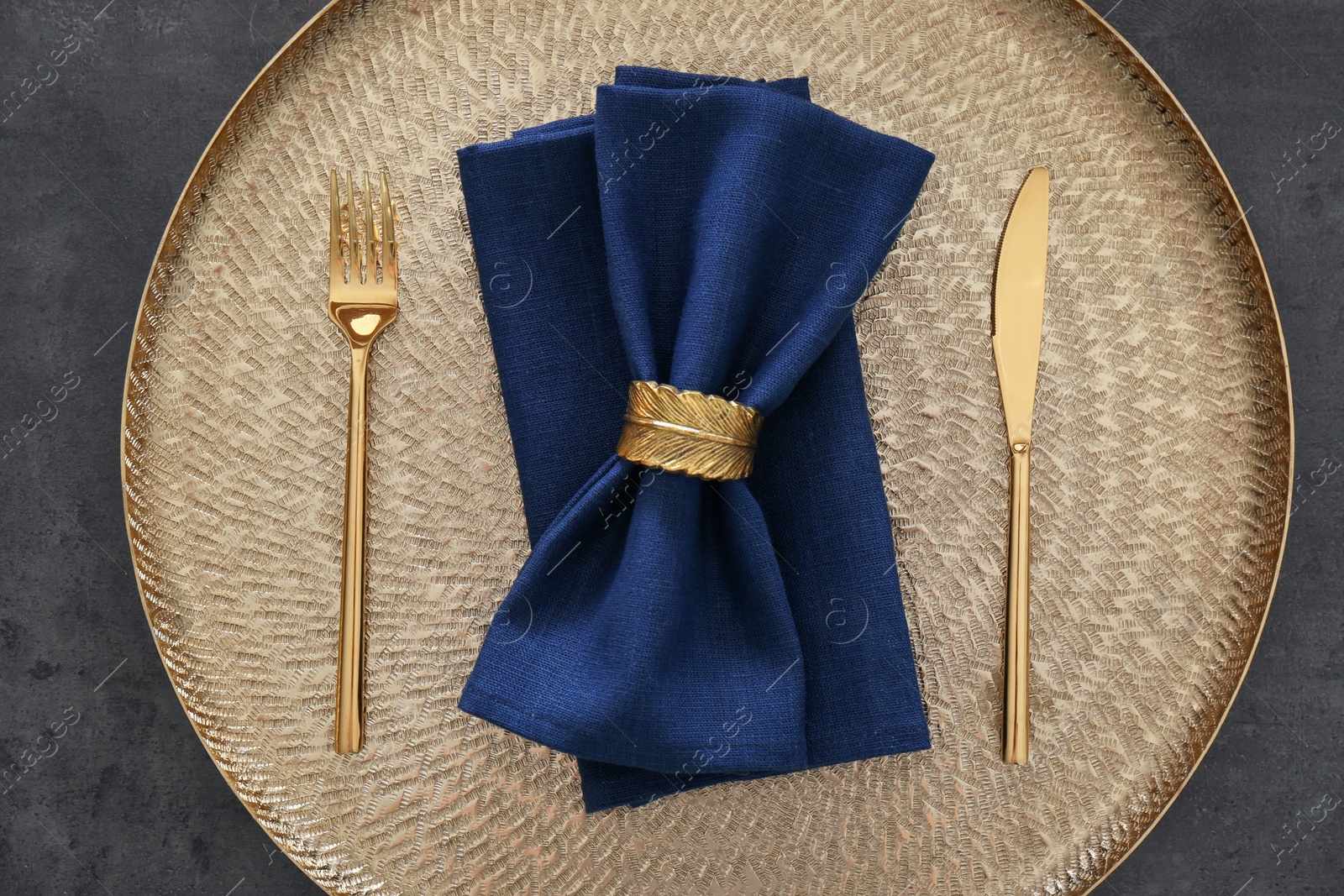 Photo of Tray with blue napkins, decorative ring and cutlery on grey table, top view