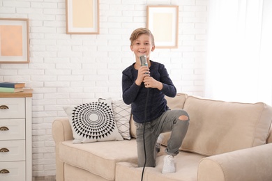 Cute boy with microphone on sofa in living room