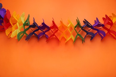Rainbow paper garland on orange background, top view with space for text. LGBT pride