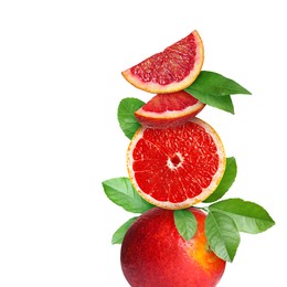 Stacked cut and whole red oranges with green leaves on white background