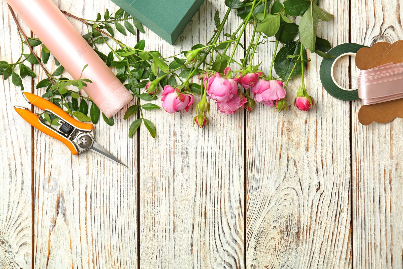 Photo of Florist equipment with flowers on wooden background, top view