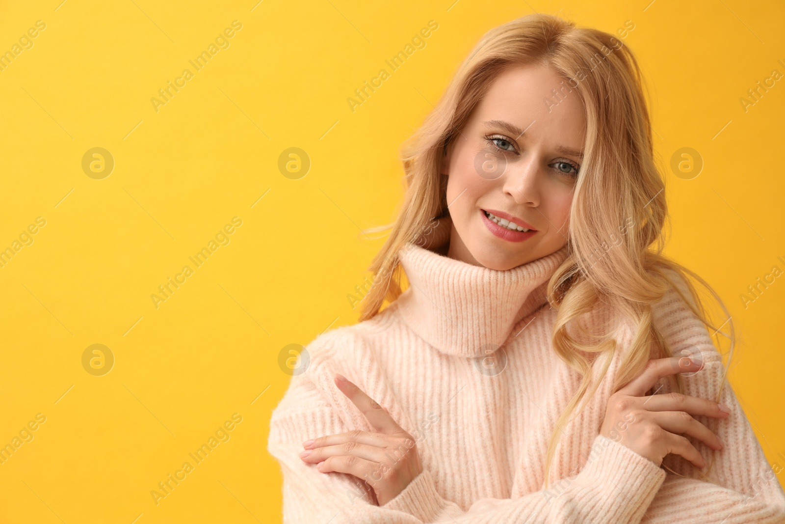 Photo of Beautiful young woman wearing warm pink sweater on yellow background. Space for text