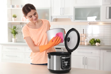 Photo of Woman cleaning modern multi cooker at table in kitchen