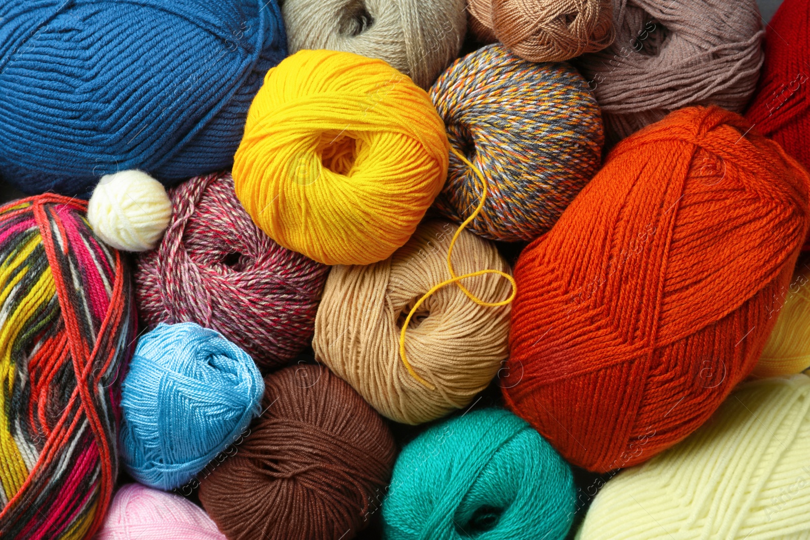 Photo of Different balls of woolen knitting yarns as background, top view