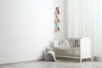 Photo of Wigwam shaped shelves over crib in baby room, space for text. Interior design