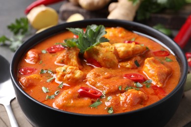 Photo of Bowl of delicious chicken curry on table, closeup