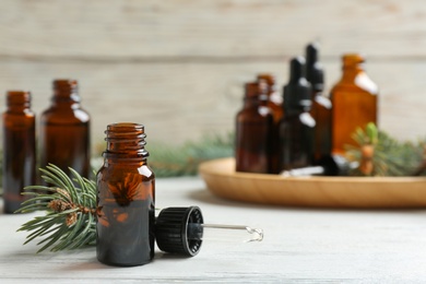 Composition with bottle of conifer essential oil on white wooden table. Space for text