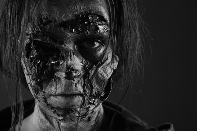 Photo of Scary zombie on dark background, black and white effect. Halloween monster