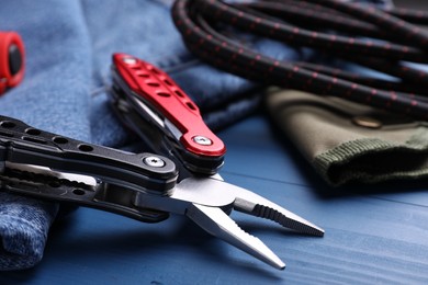 Photo of Modern compact portable multitool and accessories on blue wooden table