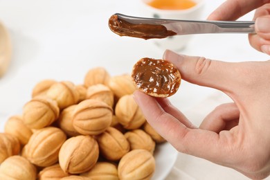 Photo of Woman spreading boiled condensed milk onto walnut shaped cookie, closeup. Space for text