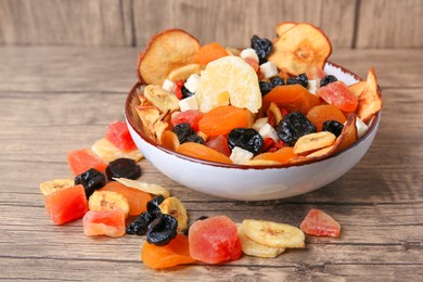 Bowl and different tasty dried fruits on wooden table