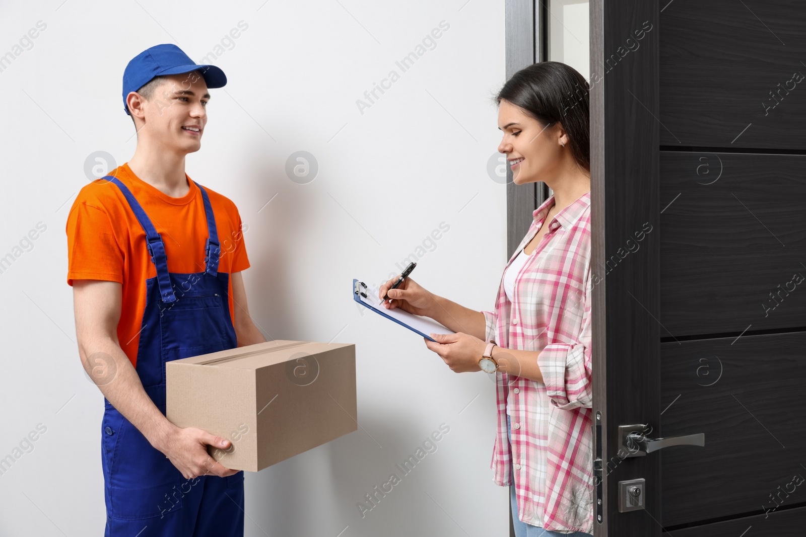 Photo of Woman receiving parcel from courier at home