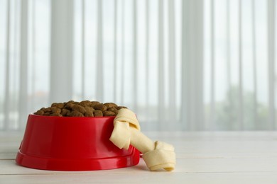 Chew bone and dry dog food on white wooden surface indoors, space for text