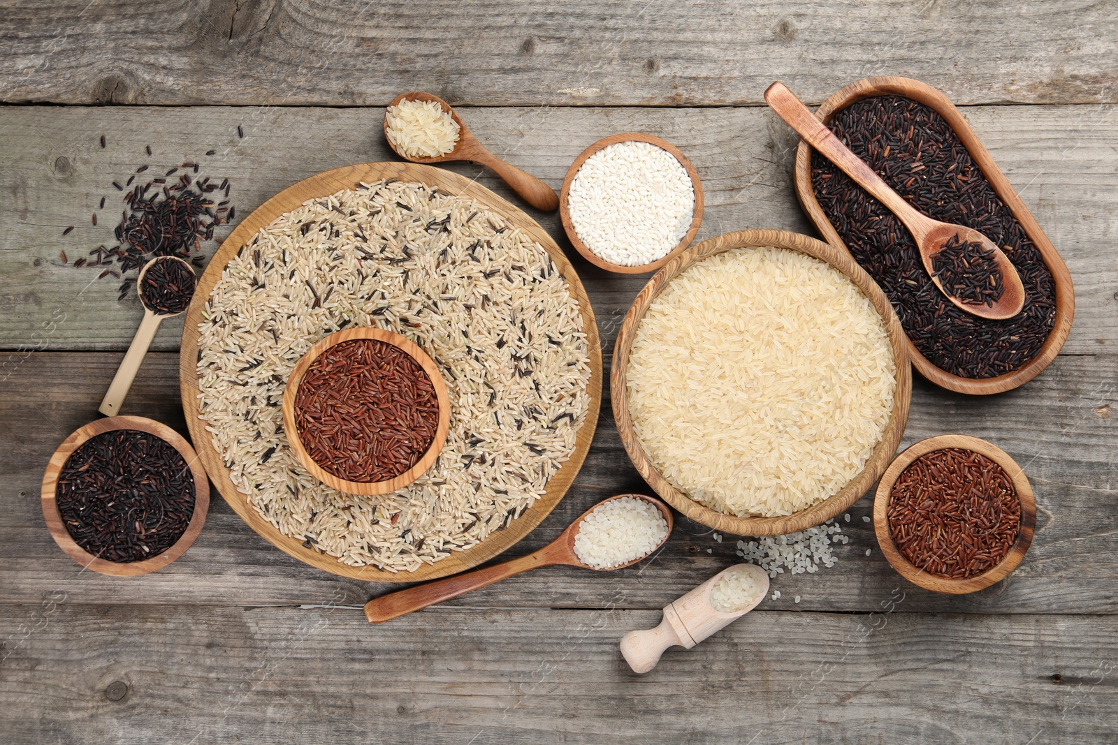 Photo of Different sorts of rice on wooden table, flat lay