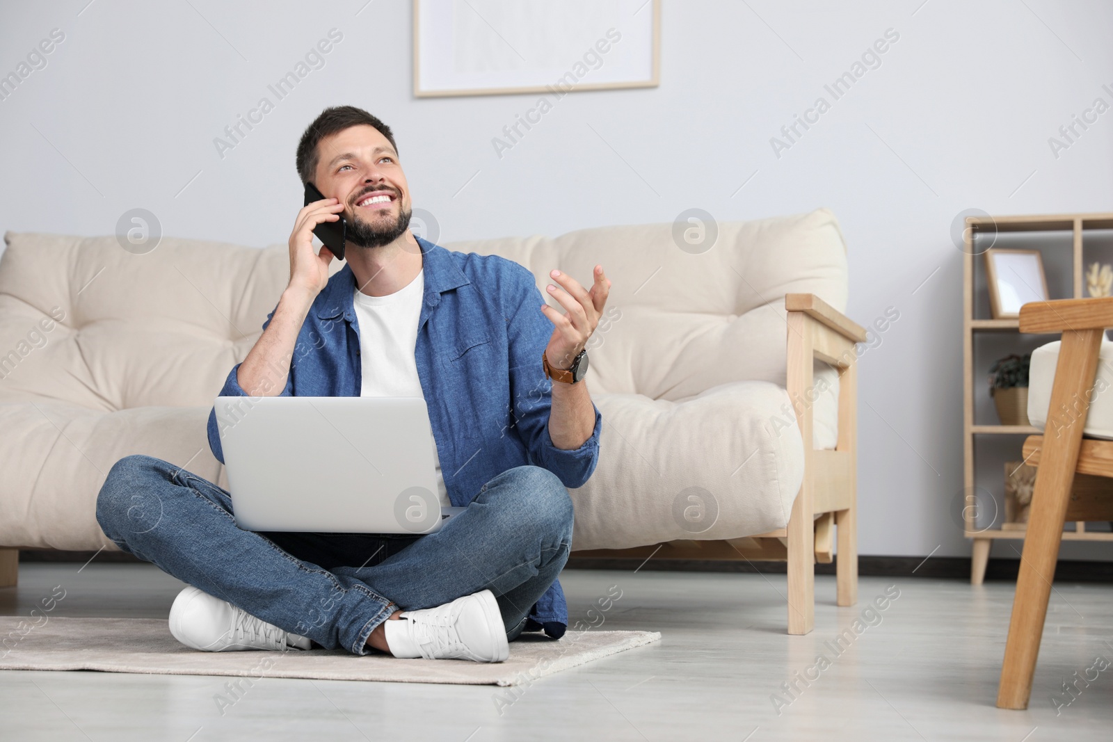 Photo of Happy man using smartphone while working with laptop at home, space for text