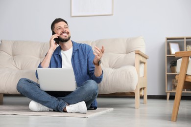 Photo of Happy man using smartphone while working with laptop at home, space for text