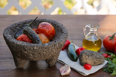 Ingredients for tasty salsa sauce, pestle and mortar on wooden table outdoors
