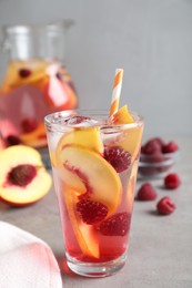 Photo of Delicious peach lemonade with soda water and raspberries on grey table. Fresh summer cocktail