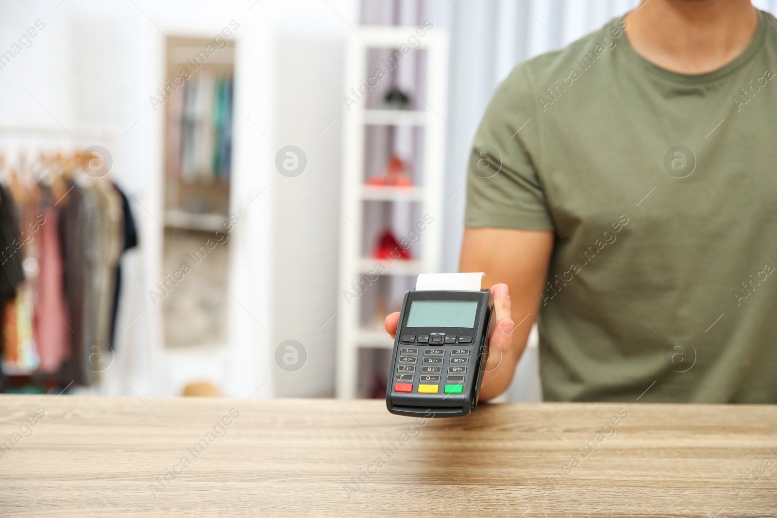 Photo of Male shop assistant with payment terminal at counter, closeup. Space for text