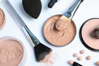 Flat lay composition with skin foundation, powder and beauty accessories on white background