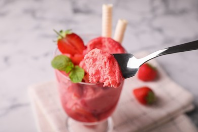 Photo of Eating delicious strawberry ice cream at table, closeup