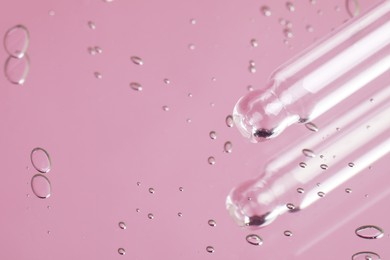 Pipette near serum drops on beautiful mirror, closeup with space for text. Toned in pink