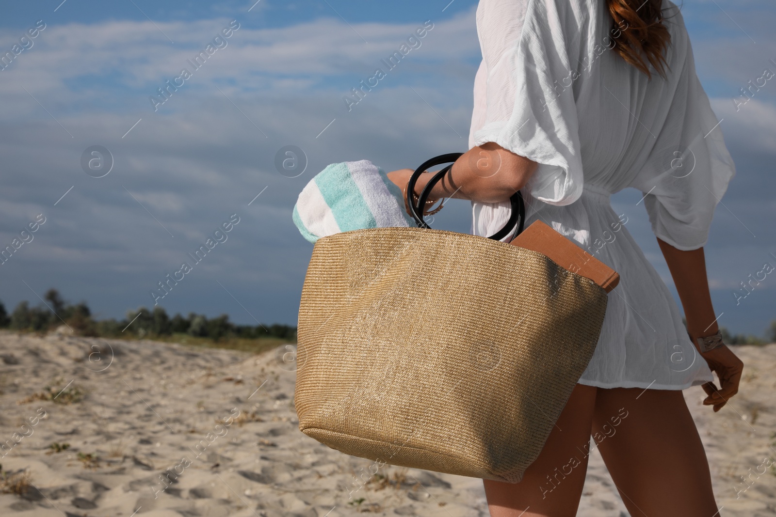 Photo of Woman carrying bag with beach towel on sand, closeup