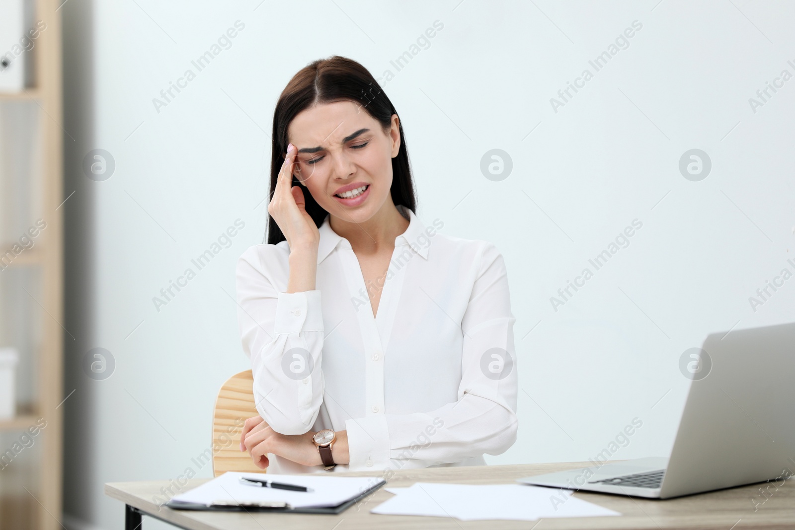 Photo of Woman suffering from migraine at workplace in office