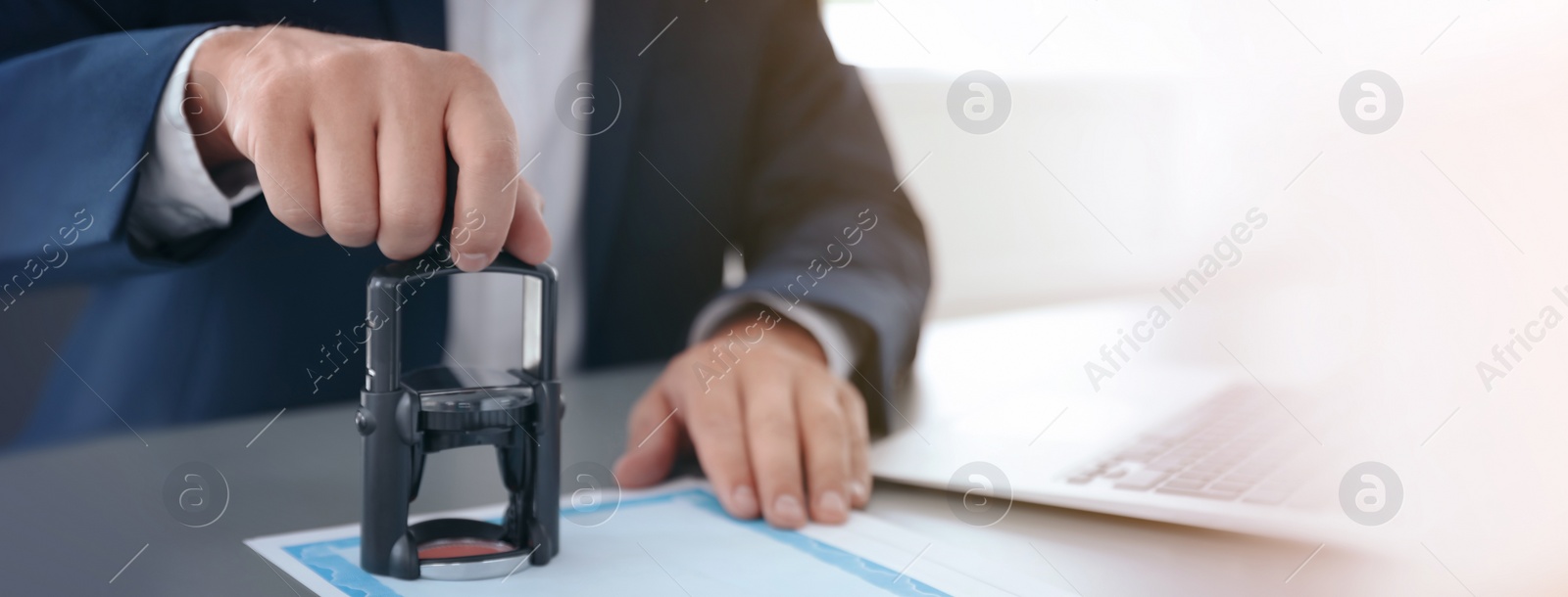 Image of Male lawyer stamping document at desk in office, closeup. Banner design