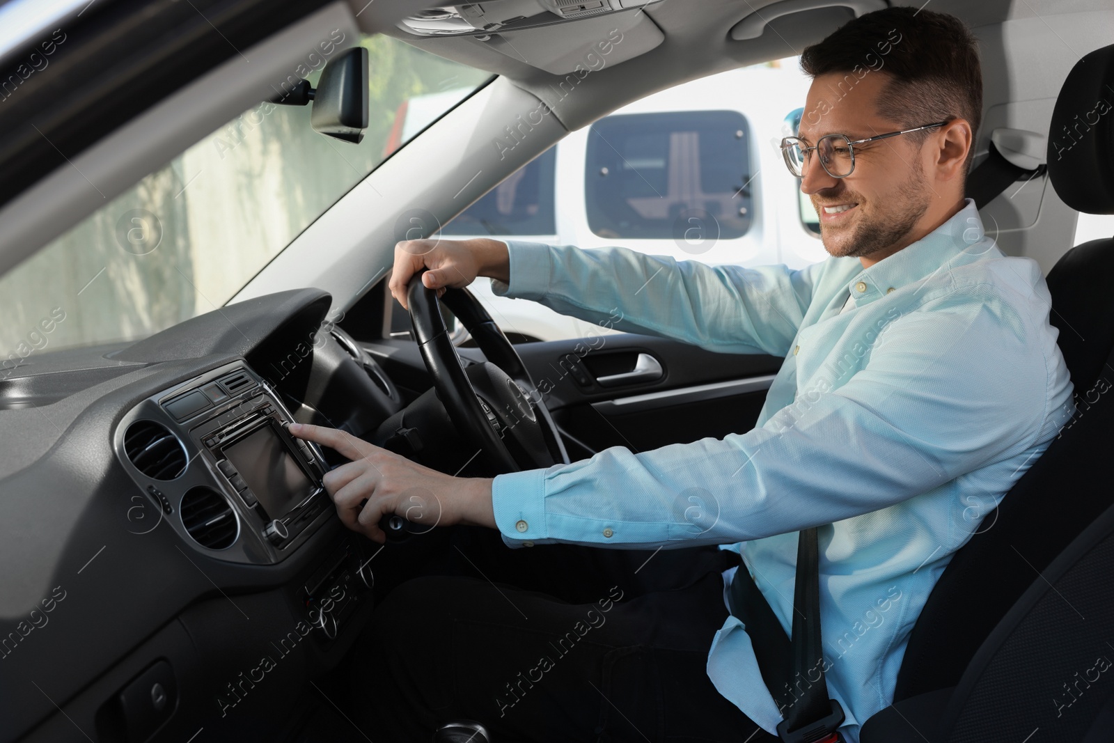 Photo of Choosing favorite radio. Handsome man pressing button on vehicle audio in car