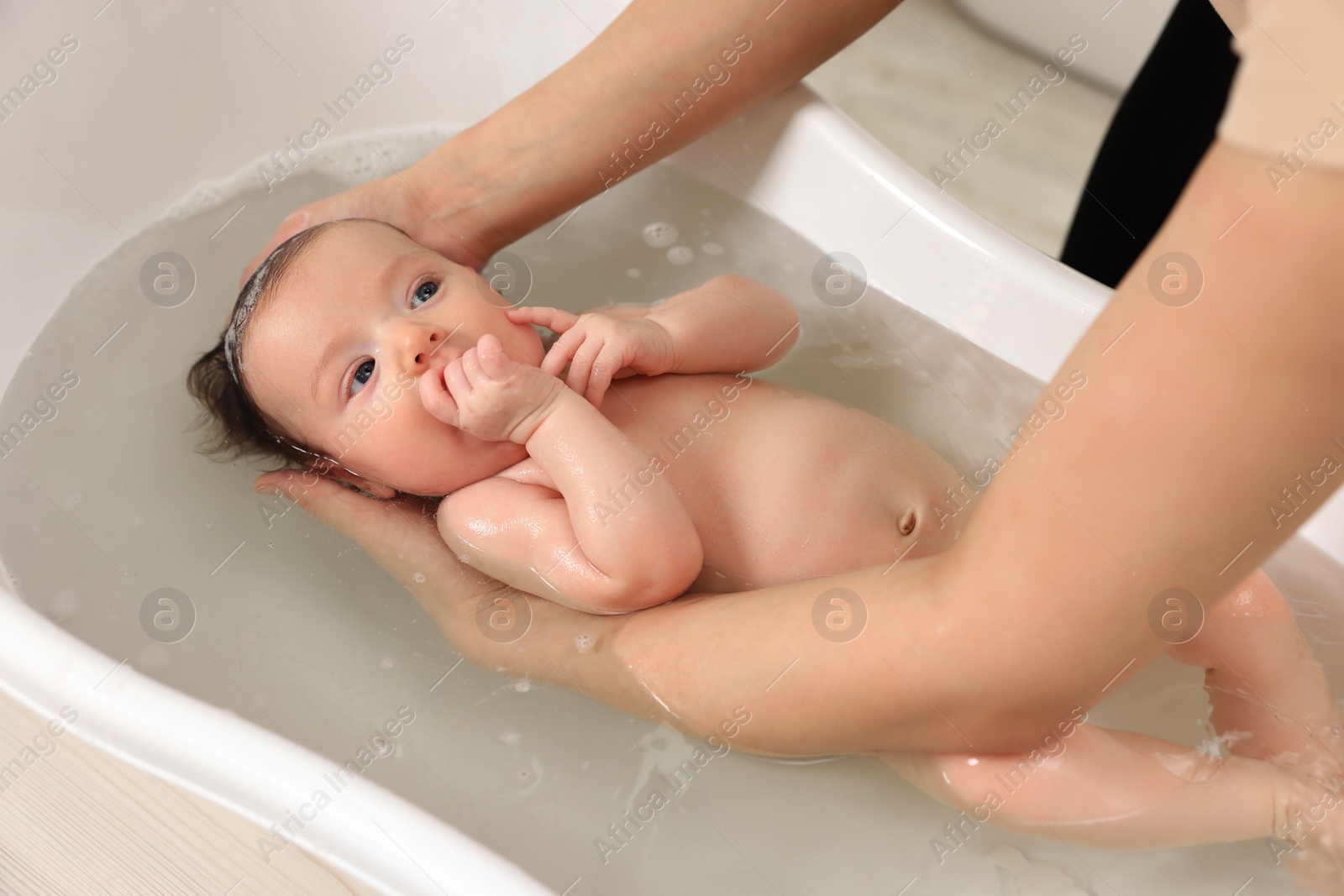 Photo of Mother bathing her little baby in bathtub, closeup