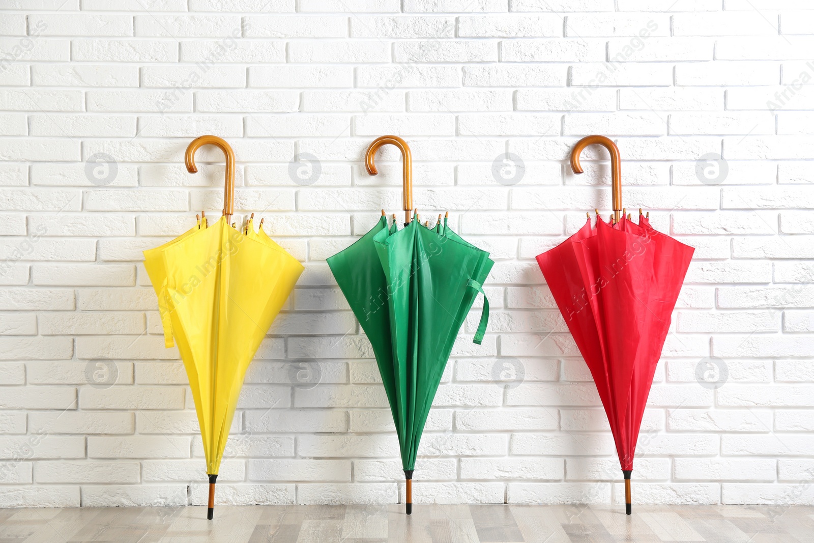 Photo of Beautiful colorful umbrellas near white brick wall