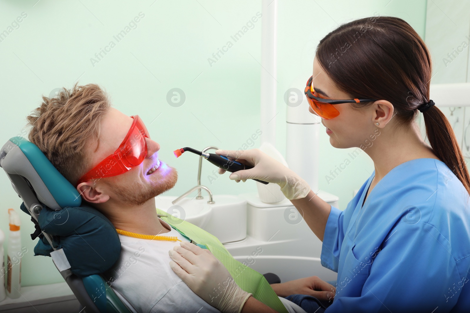 Photo of Professional dentist working with patient in modern clinic. Teeth whitening