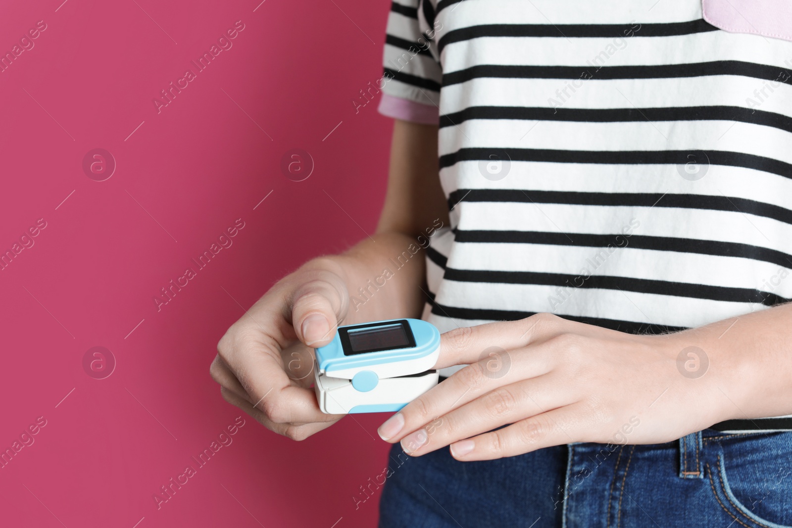 Photo of Young woman checking pulse with digital medical device on color background, closeup. Space for text