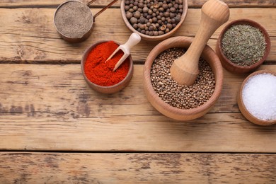 Photo of Mortar with pestle and different spices on wooden table, above view. Space for text