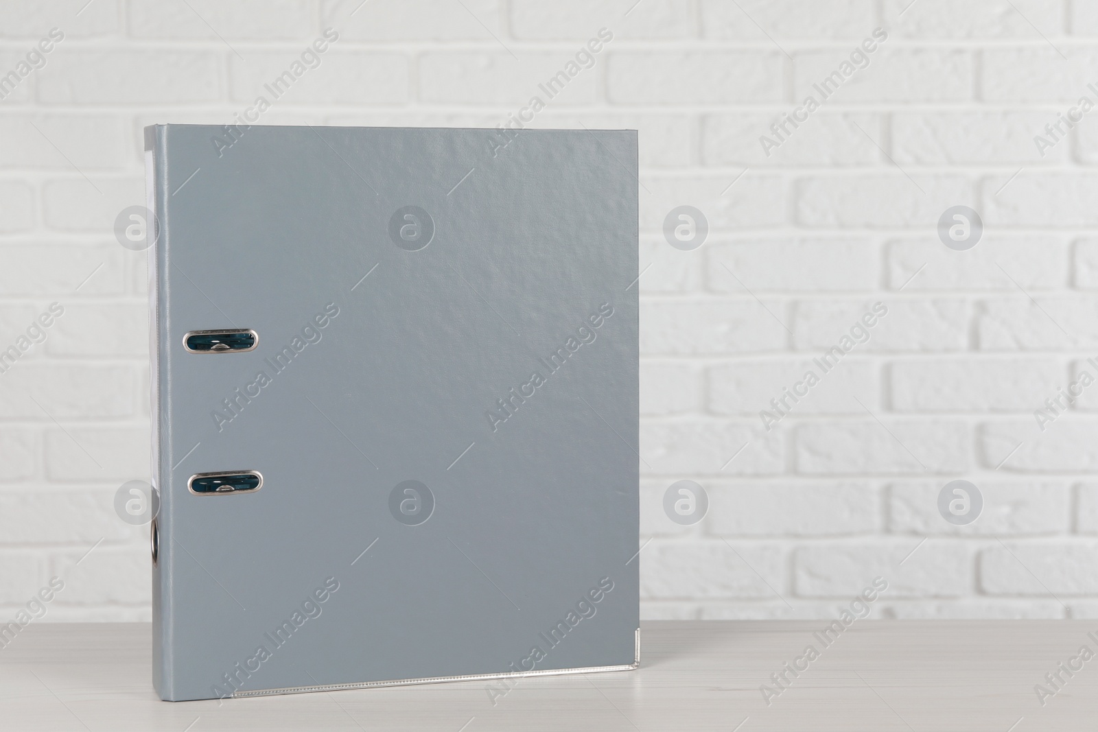 Photo of Office folder on wooden table near white brick wall, space for text