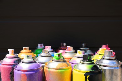 Photo of Used cans of spray paint on dark background, space for text. Graffiti supplies